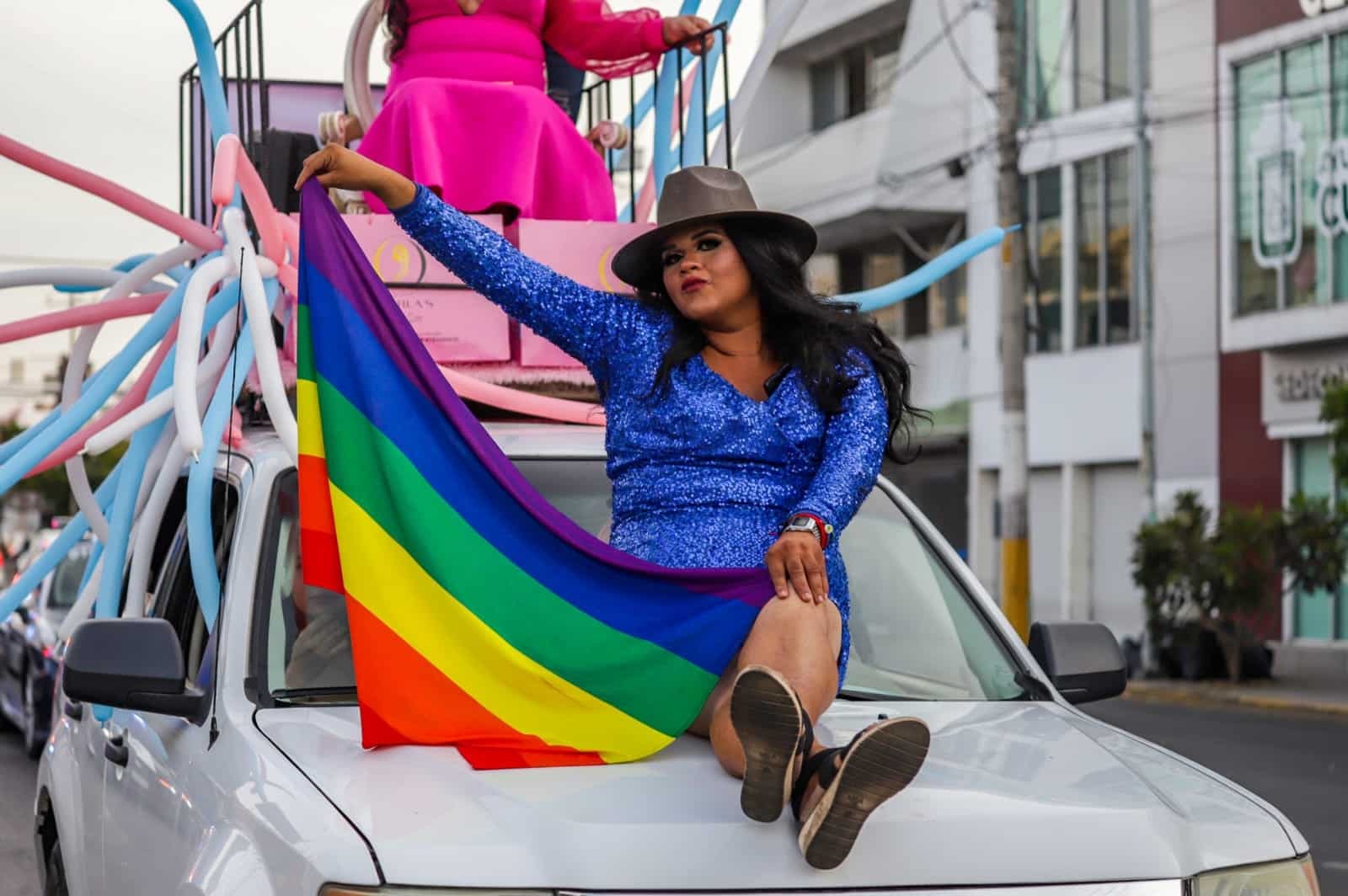Una persona con la bandera LGBT en un carro