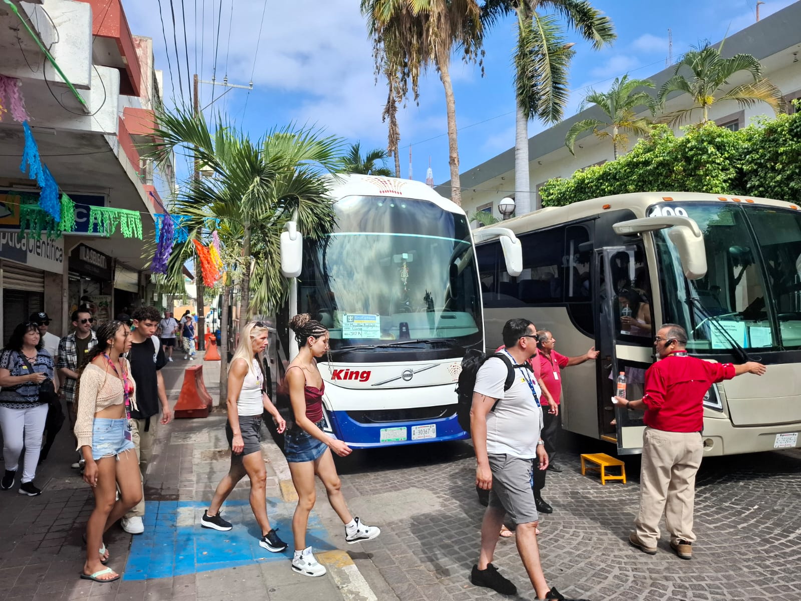 Turistas cruzando calle con autobuses