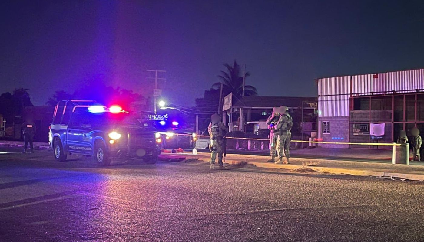 Patrullas con las luces encendidas y agentes militares desplegados en una calle con una cinta de precaución, de noche