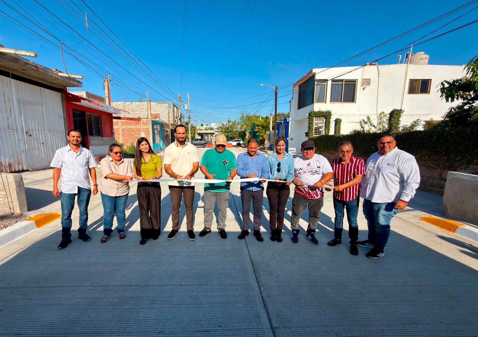 Funcionarios cortando un listón en una calle pavimentada