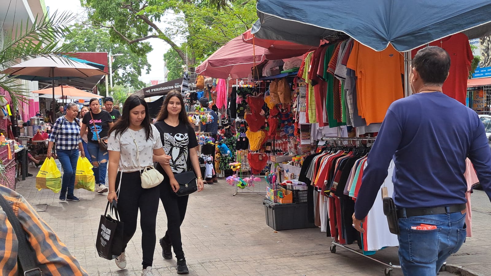 Personas caminando entre puestos de comercio informal