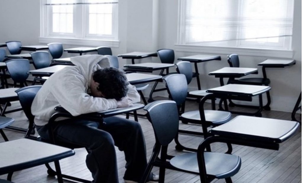Persona sentada en un salón de clases vacío