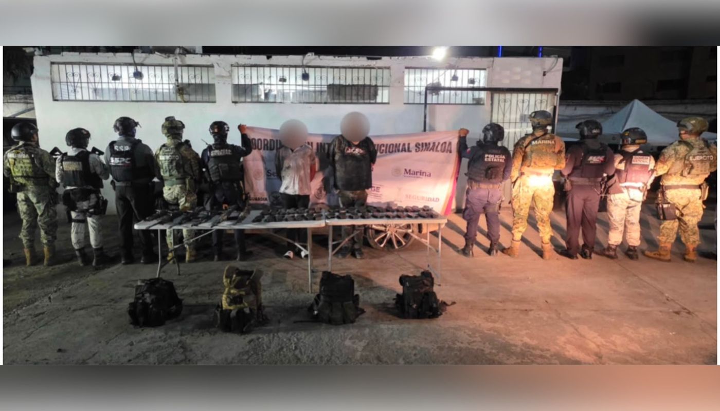 Agentes de seguridad de espaldas y al centro los detenidos con las manos esposadas en la espalda, al frente una mesa con objetos y armas