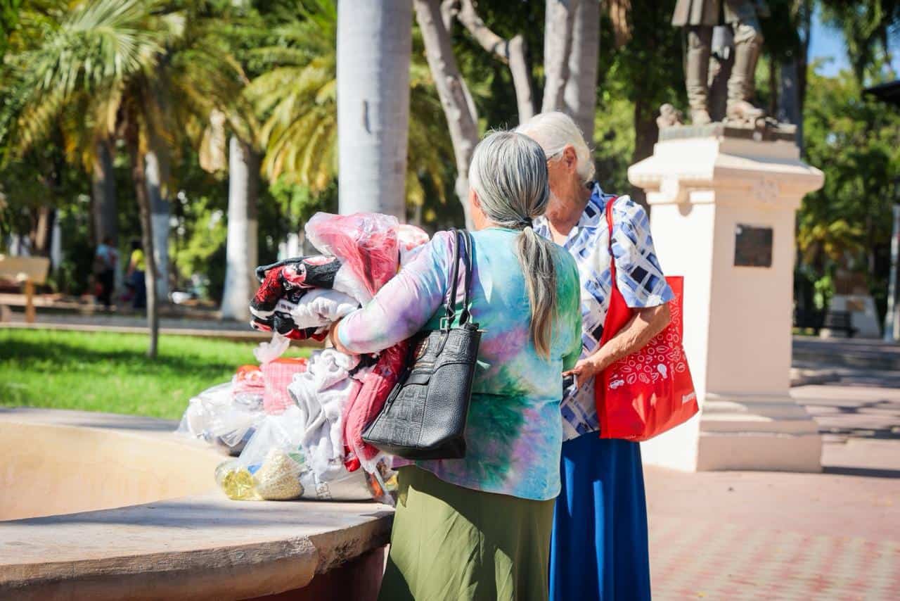 Dos personas mujeres en una zona de plazuela con despensas