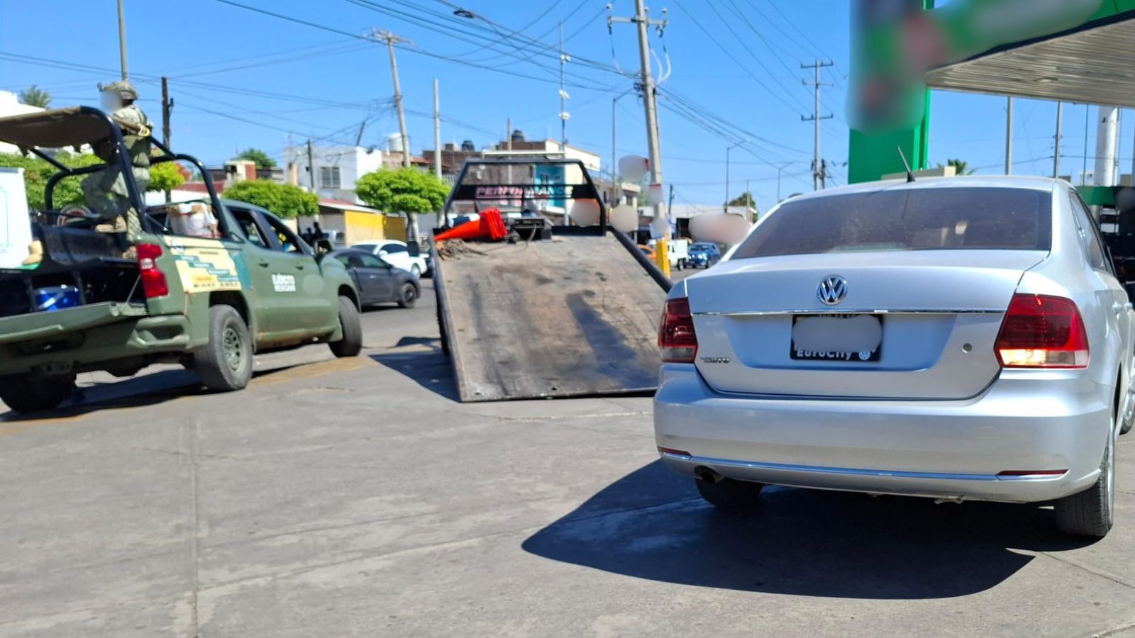Carro gris y una unidad del Ejército en una gasolinera
