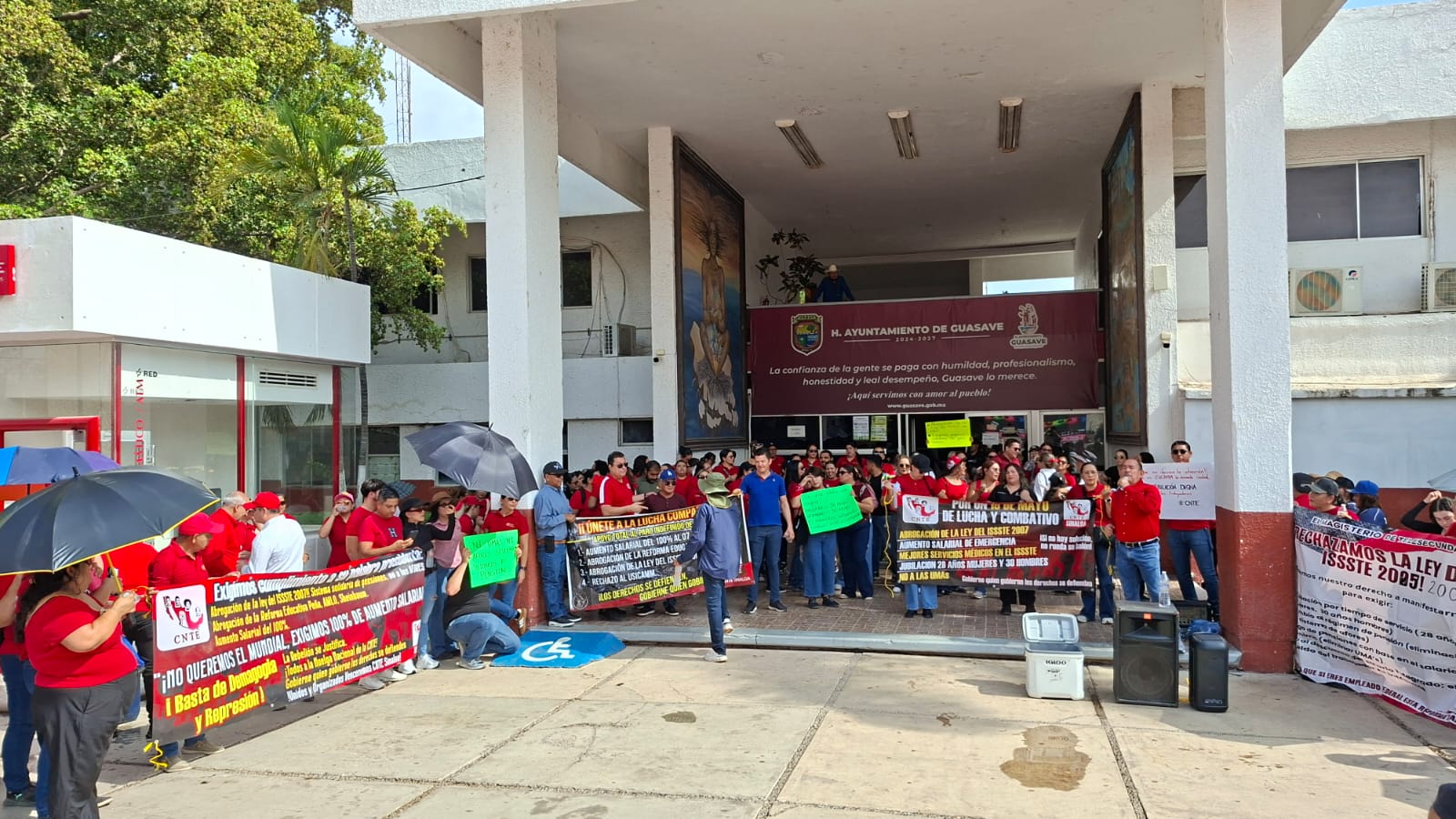 Personas realizando una manifestación con pancartas afuera de una institución de Gobierno