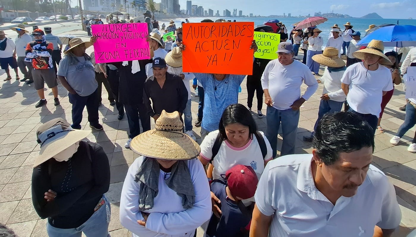 Personas con pancartas en el malecón de Mazatlán durante una manifestación