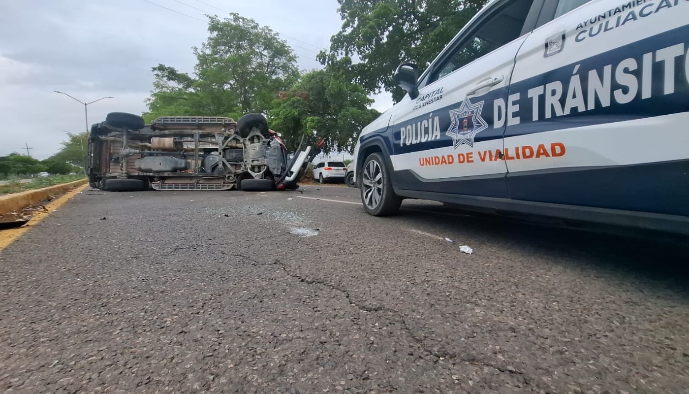 Unidad de transito municipal de Culiacán junto a una camioneta volcada sobre una carretera