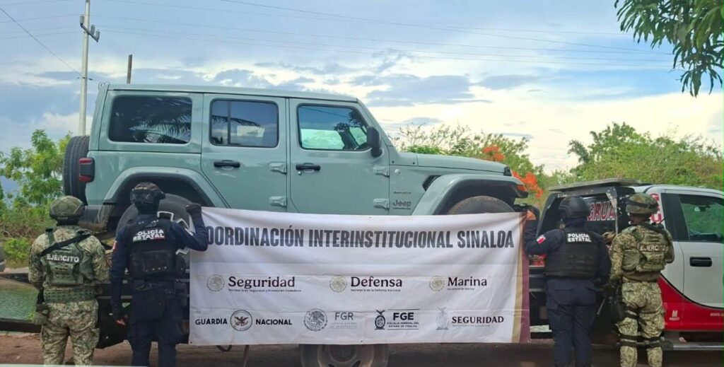 Jeep en una grúa y autoridades sosteniendo un banner
