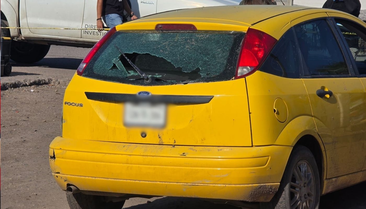 Carro amarillo con el cristal de atrás quebrado y balas en el costado de la carrocería