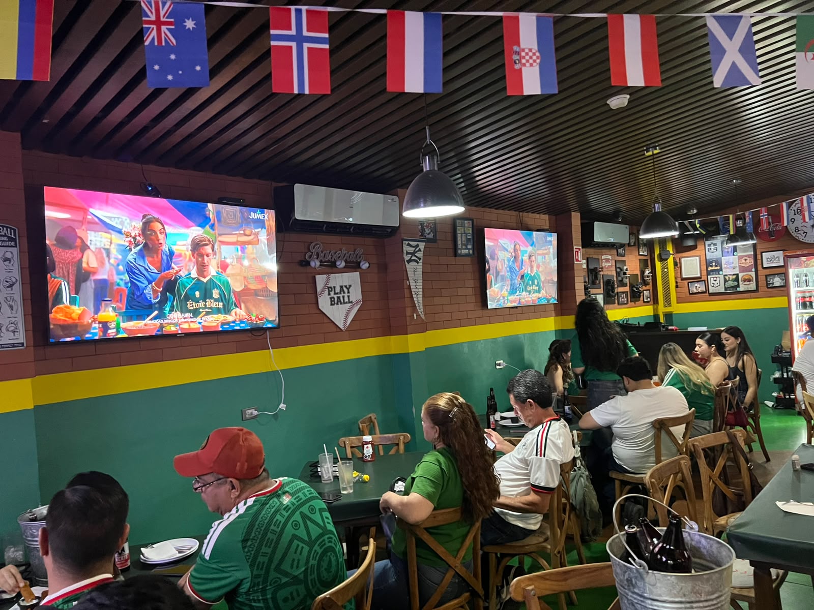 Personas sentadas junto a una televisión con banderas de paises