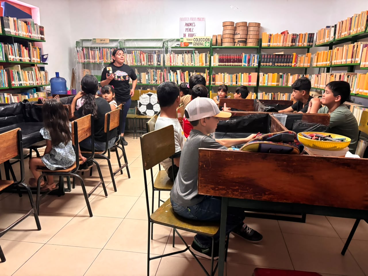 Biblioteca con nilos sentados y una maestra