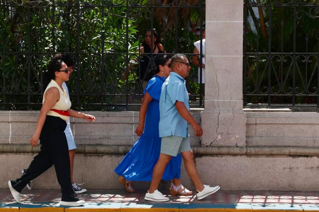 Tres personas caminando bajo el sol