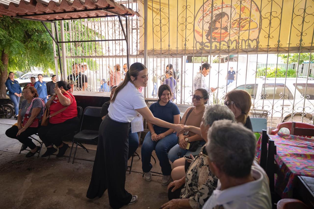 Ana Miriam Rmos saludando a una persona en una silla