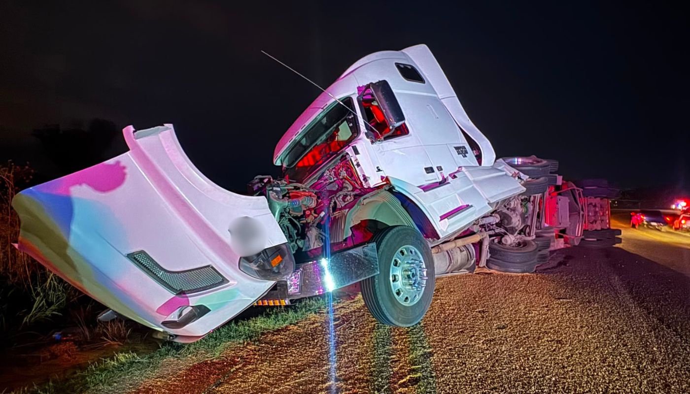 unidad de carga pesada volcada y con el frente impactado tras un accidente en una carretera de noche