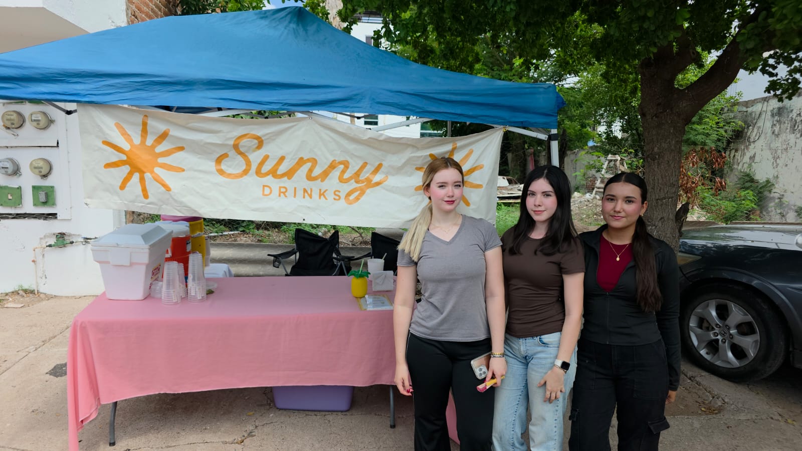 Tres estudiantes con una lona y una carpa