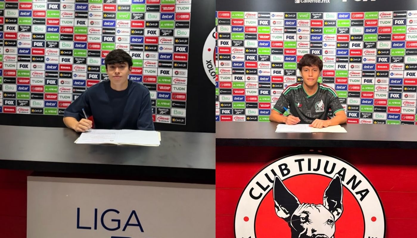 Dos jóvenes con una hoja en una mesa con el logo de Xolos de Tijuana