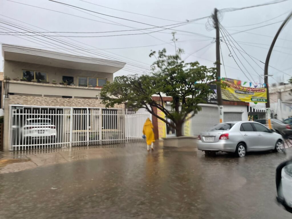 Calle inundada y una persona con impermeable amarillo