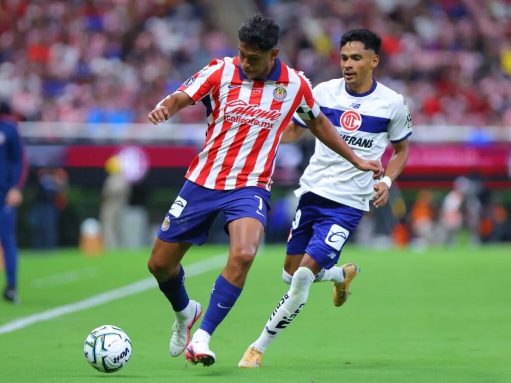 Dos jugadores de futbol, de Chivas y Toluca, en un estadio durante un partido