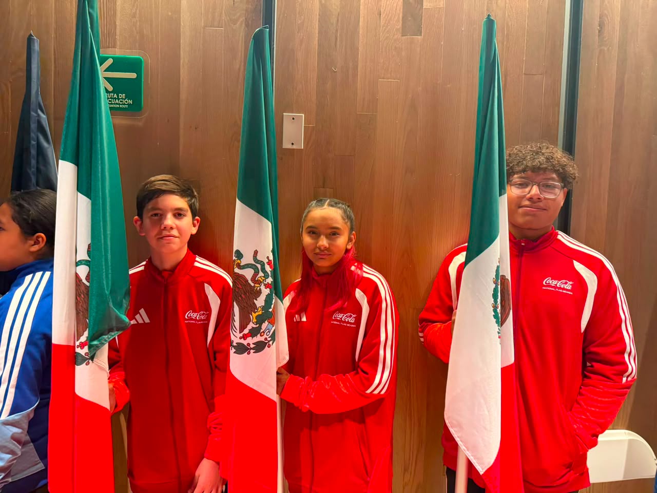 Dos niños y una niña con ropa color roja y la bandera de México