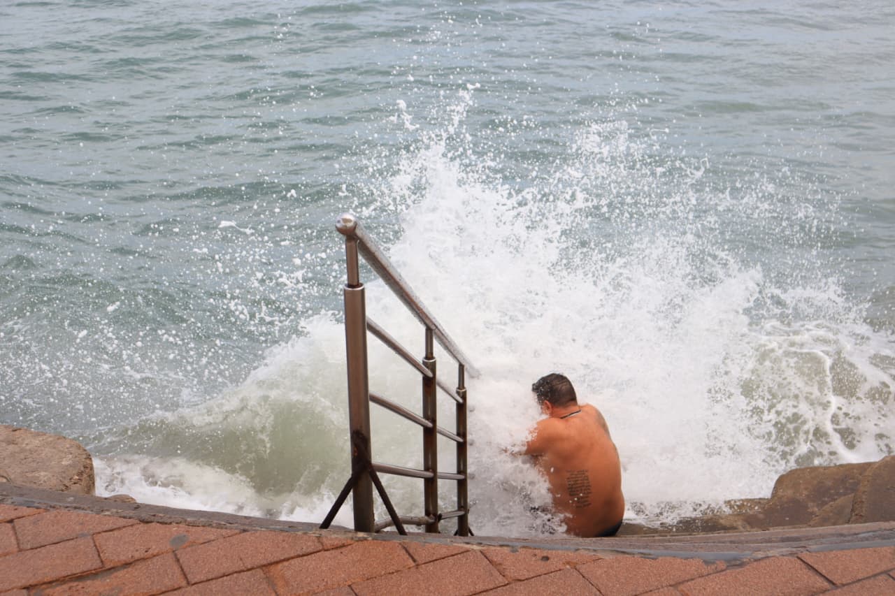 Ola junto a una persona en las escaleras del malecón de Mazatlán