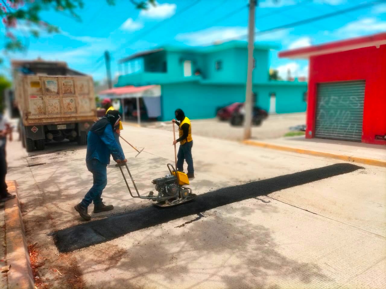 Dos personas con un camión atrás y una máquina en la calle