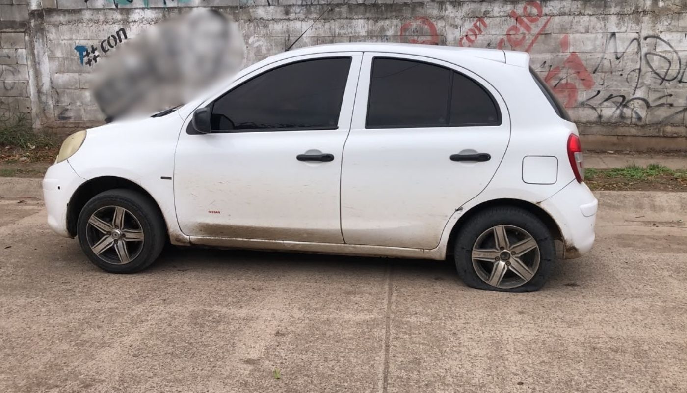 Carro blanco con la llanta de atrás ponchada