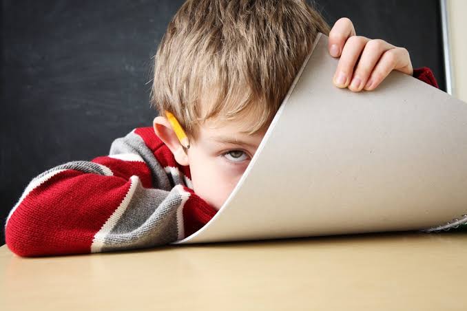 Niño con libreta tapando la cara con aparente TDAH