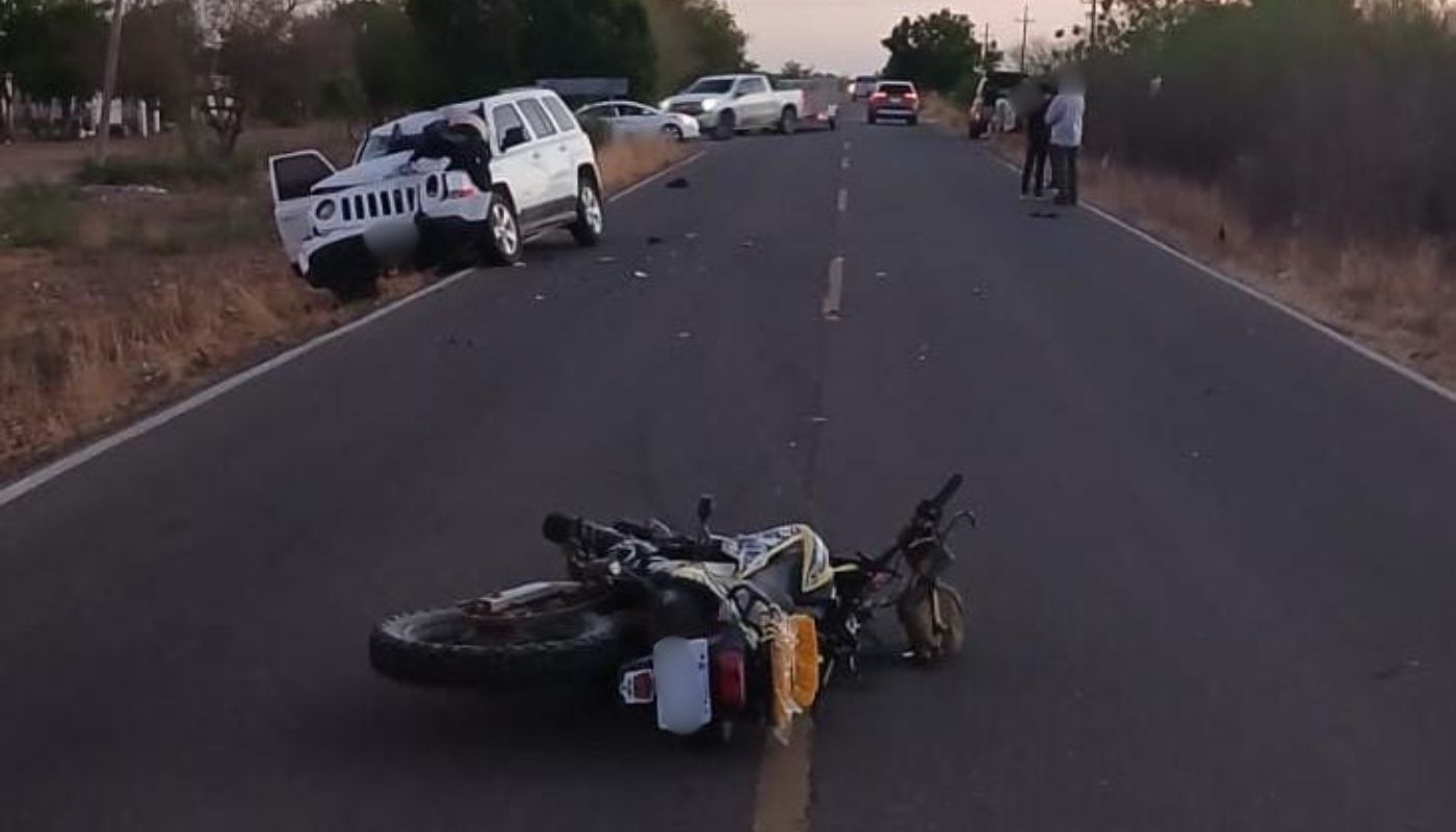 motocicleta tirada en una carretera y una camioneta blanca con un impacto en la parte frontal