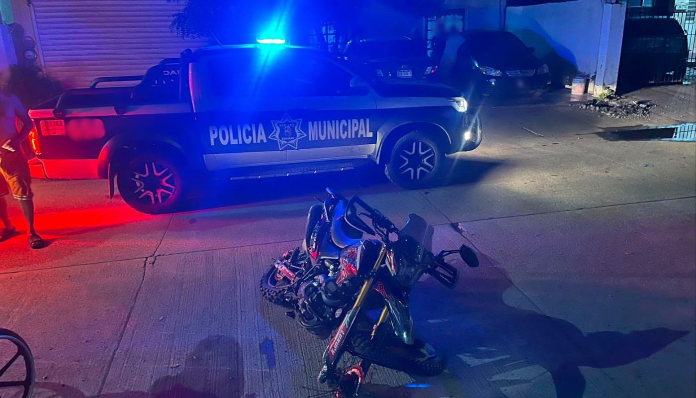 motocicleta tirada en una calle junto a una patrulla