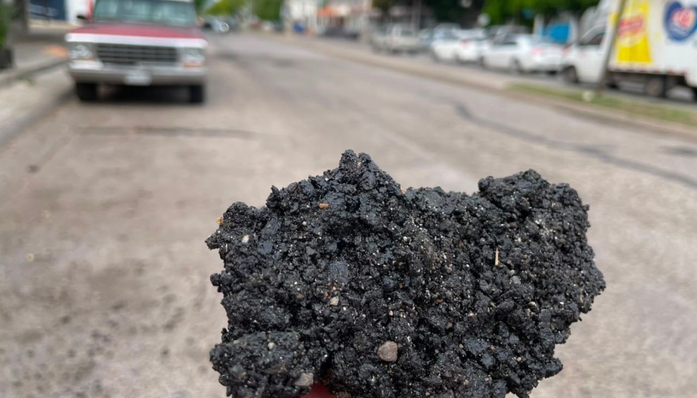 Pedazo de asfalto y al fondo una calle con carros