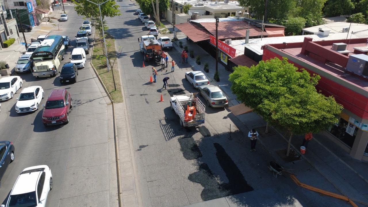 personas realizando labores de bacheo en una calle con carros