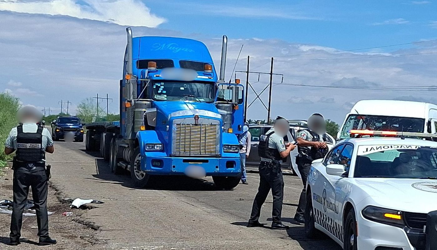 elementos de la Guardia Nacional, un tráiler azul y más carros en una carretera