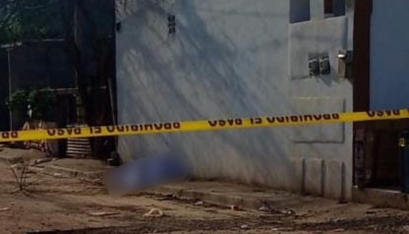 cinta amarilla de precaución frente a una barda azul de una casa