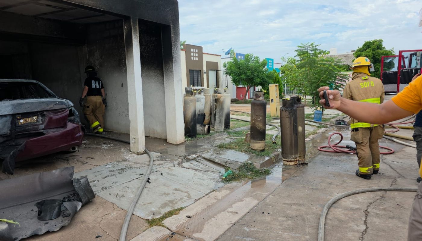Personal de bomberos y PC afuera de una casa donde hubo una explosión e incendio de cilindros de gas LP