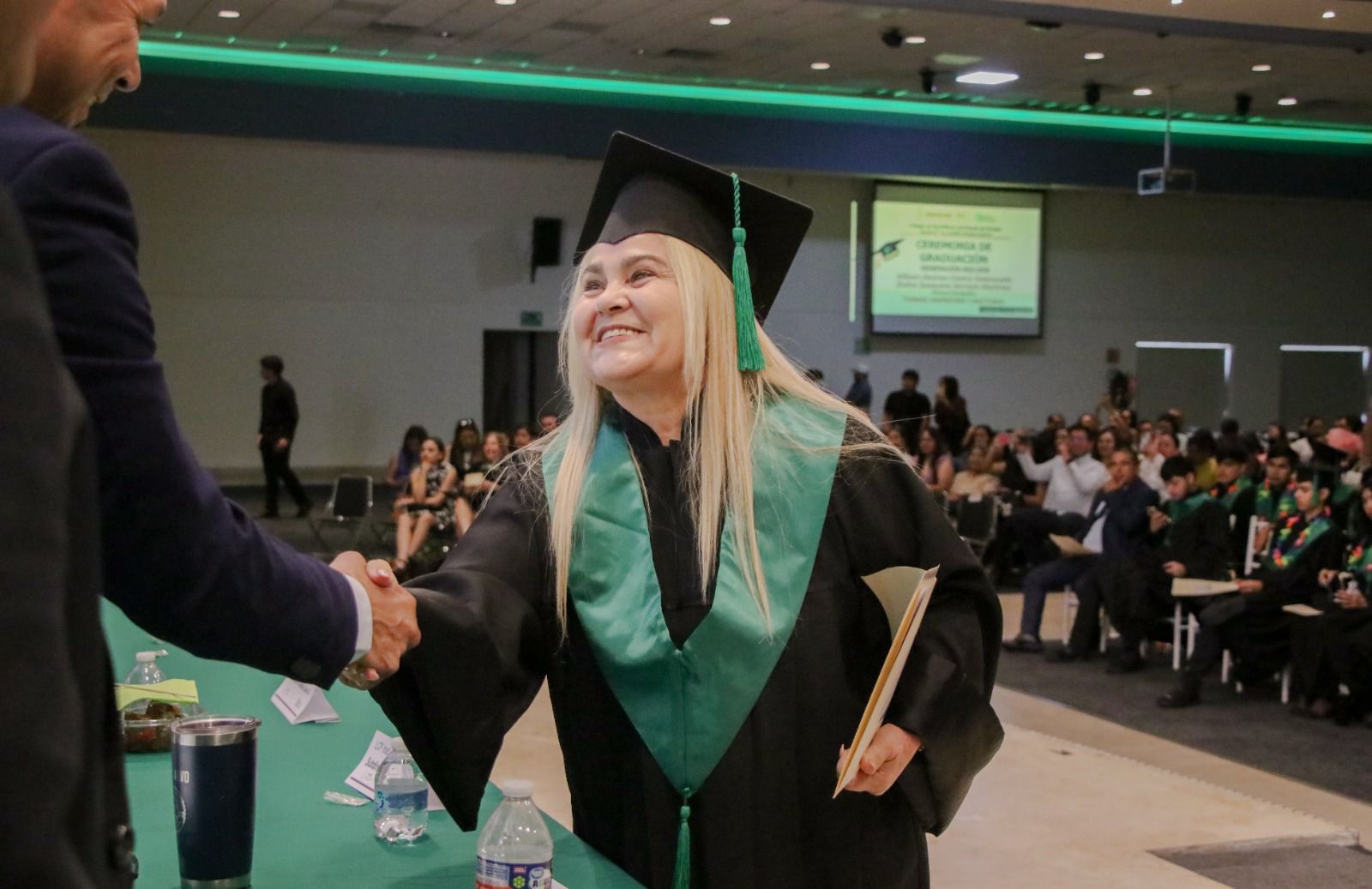 Mujer recibiendo papeles en su graduación de preparatoria Cobaes