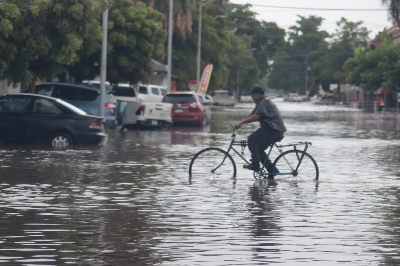 Persona en bicicleta pasando por una calle inundada