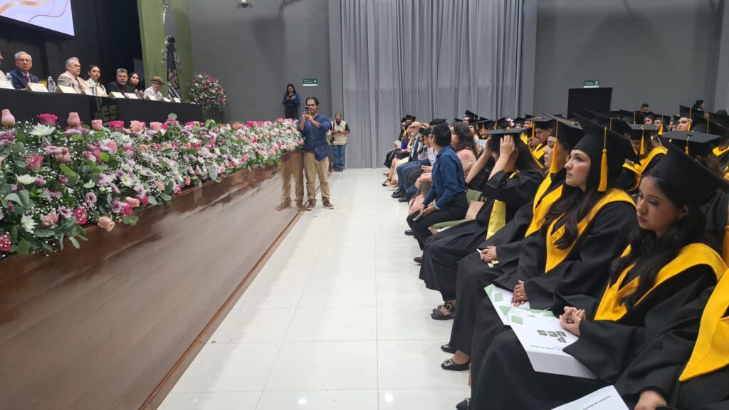 Flores y un escenario junto a personas graduadas