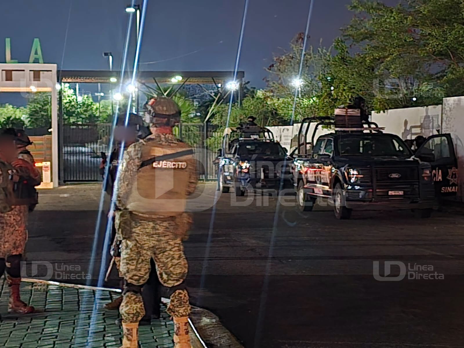 Unidad policiaca y elementos afuera de un edificio de departamentos en la noche