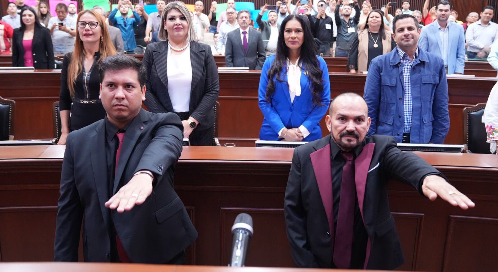 Dos personas toman protesta con el brazo arriba