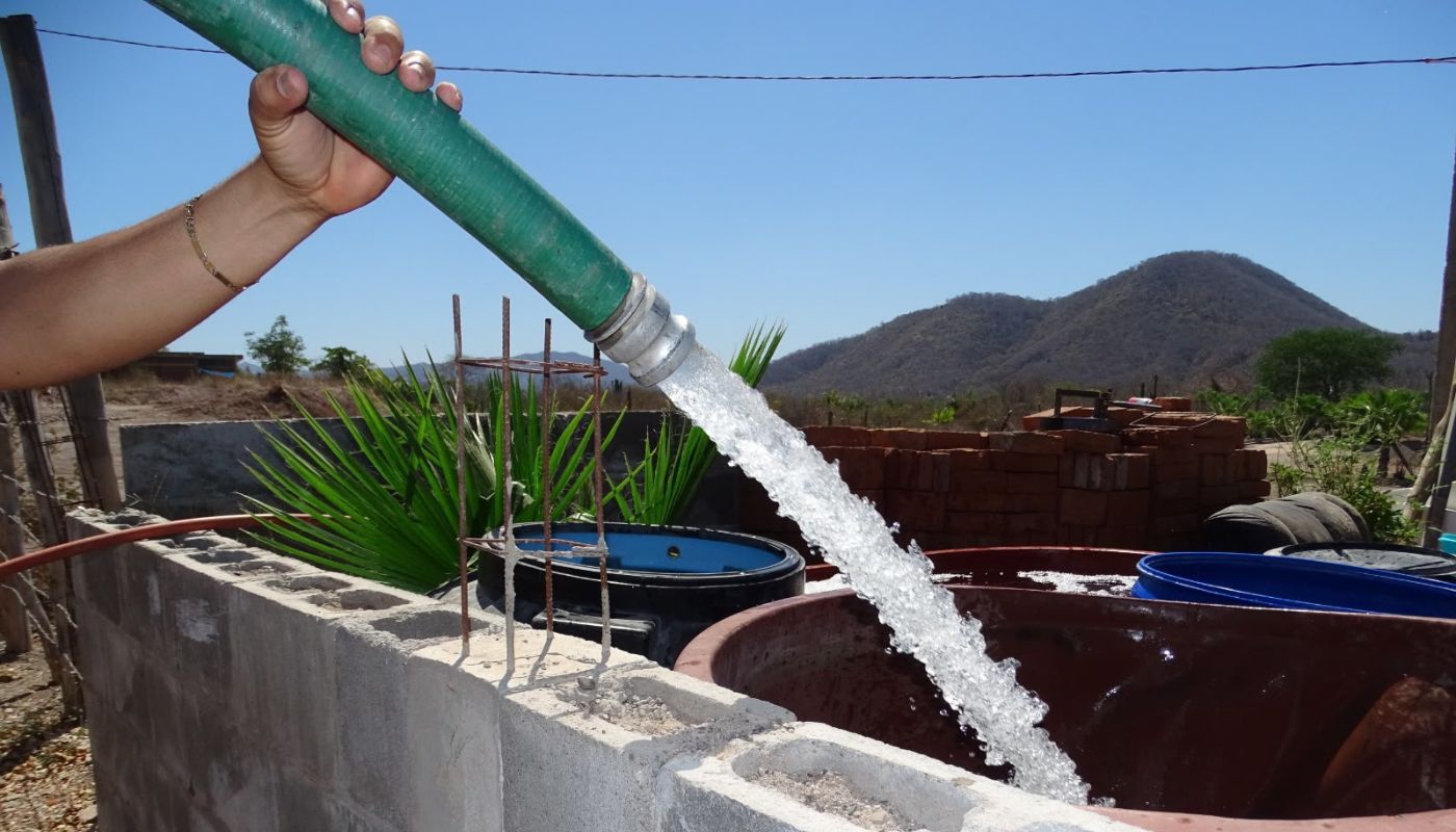 mano de una persona sosteniendo una manguera que vierte agua en una tina