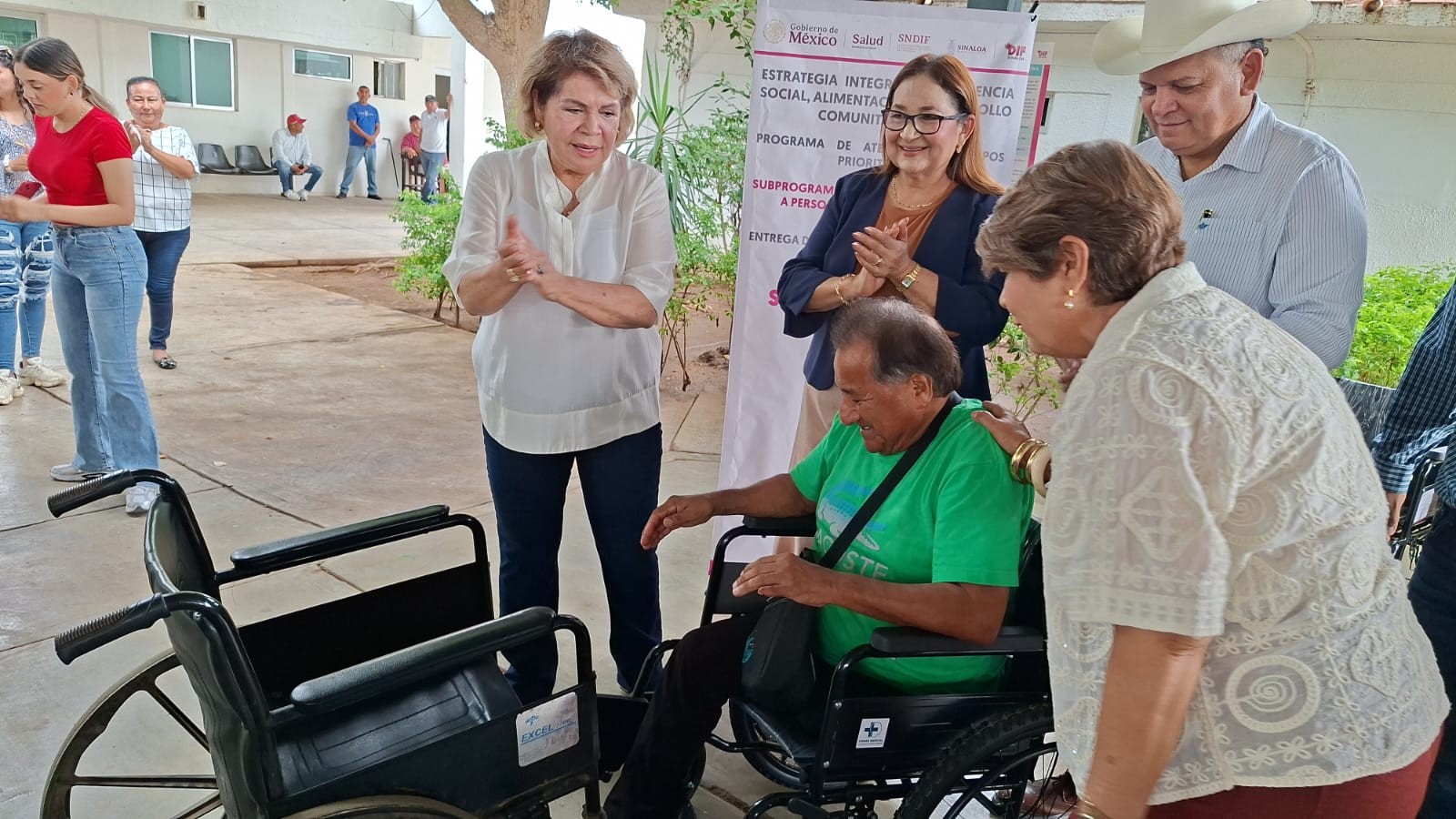 personas de pie junto a una persona en silla de ruedas